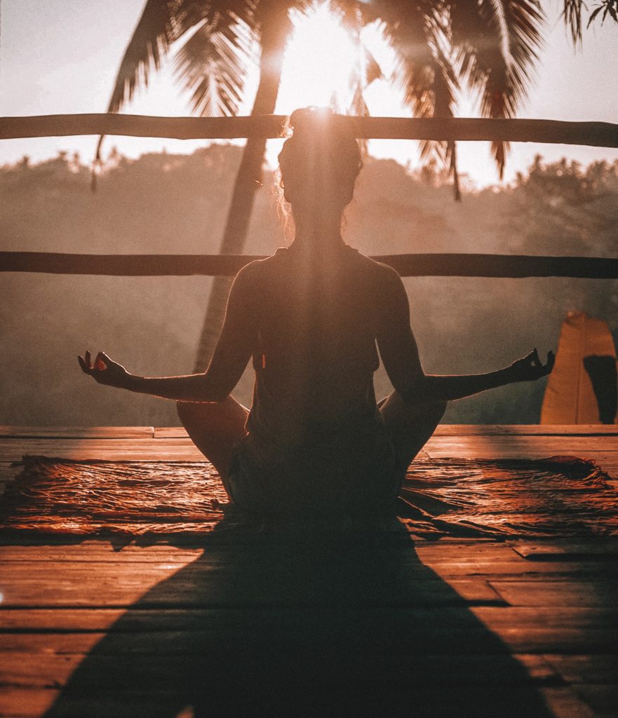 Female sitting in a yoga pose at sunset.